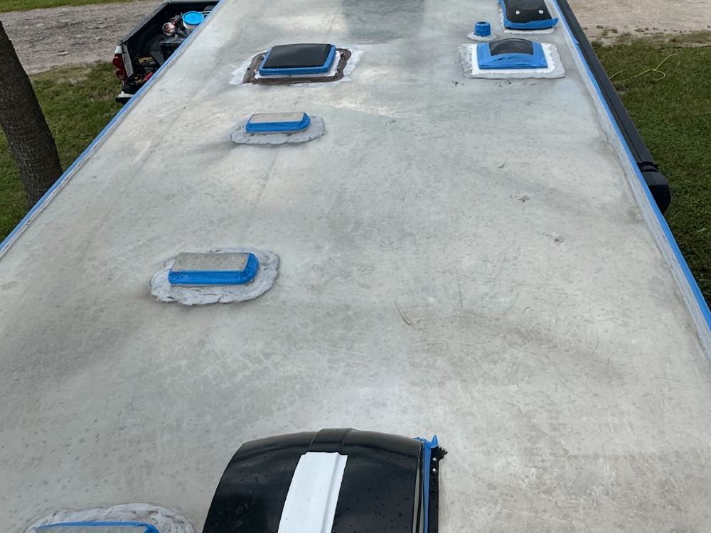 Trailer roof masked with blue tape around every vent and skylight before coating